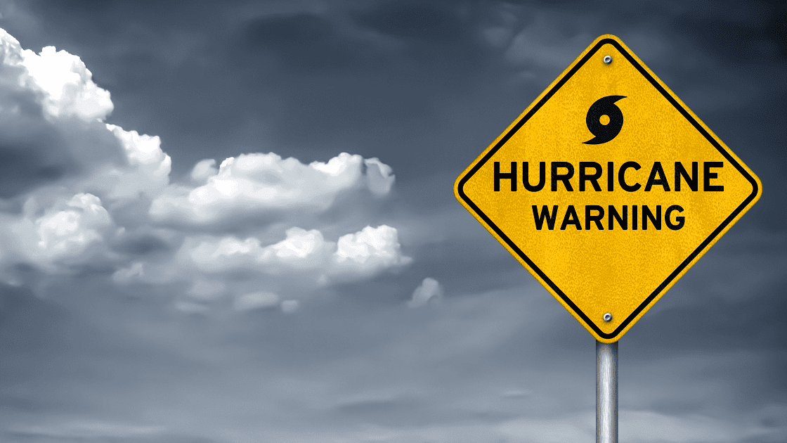 Yellow hurricane warning sign against cloudy sky