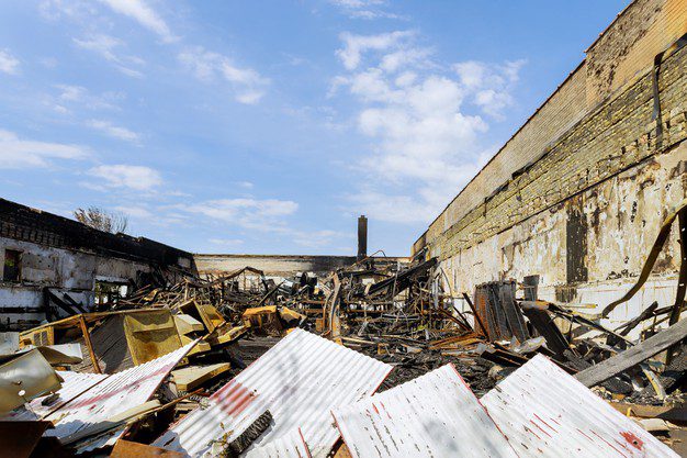 Burned industrial building rubble under blue sky