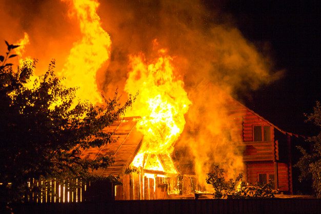Nighttime wooden house ablaze with flames