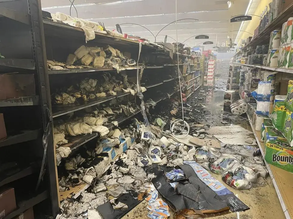 Burned grocery store aisle with debris.