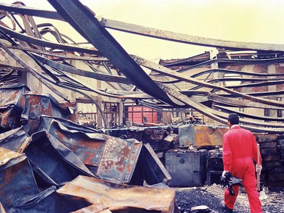 Man walking through burnt industrial ruins.
